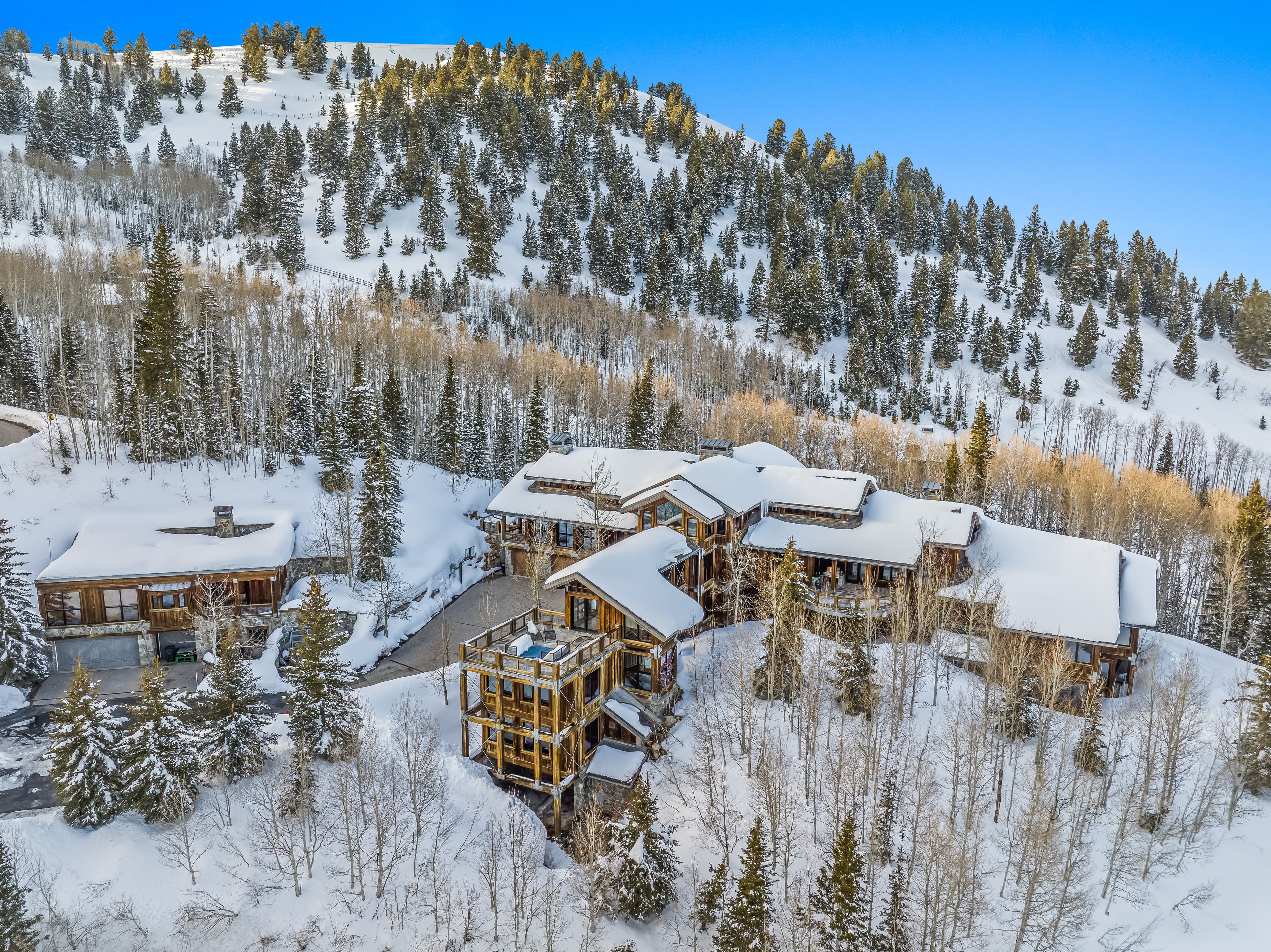 An external view of this luxury Park City vacation rental covered in snow, with a mountain view behind.