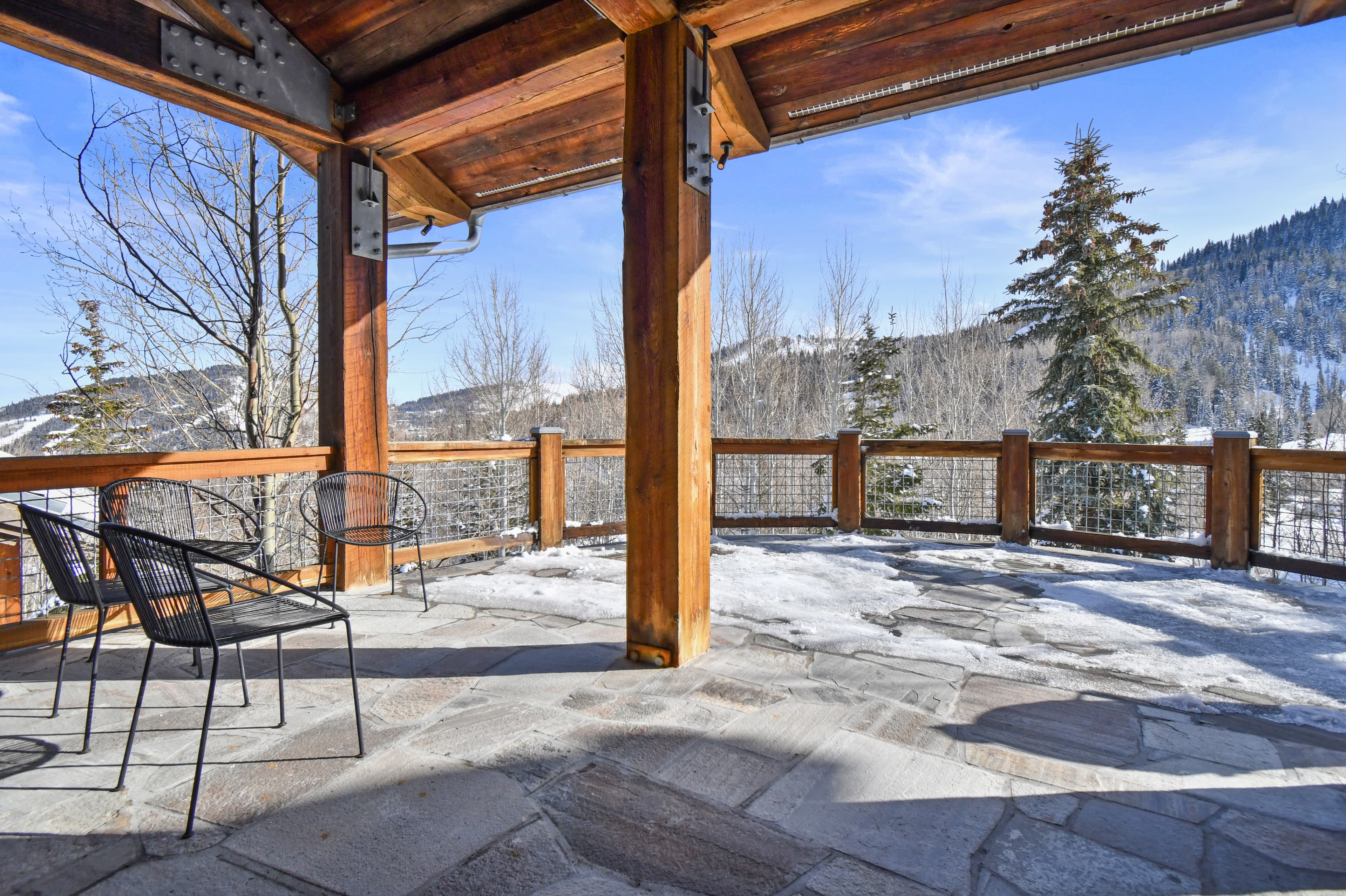 Snow builds up on the patio of the home, two chairs facing it from under the roof.