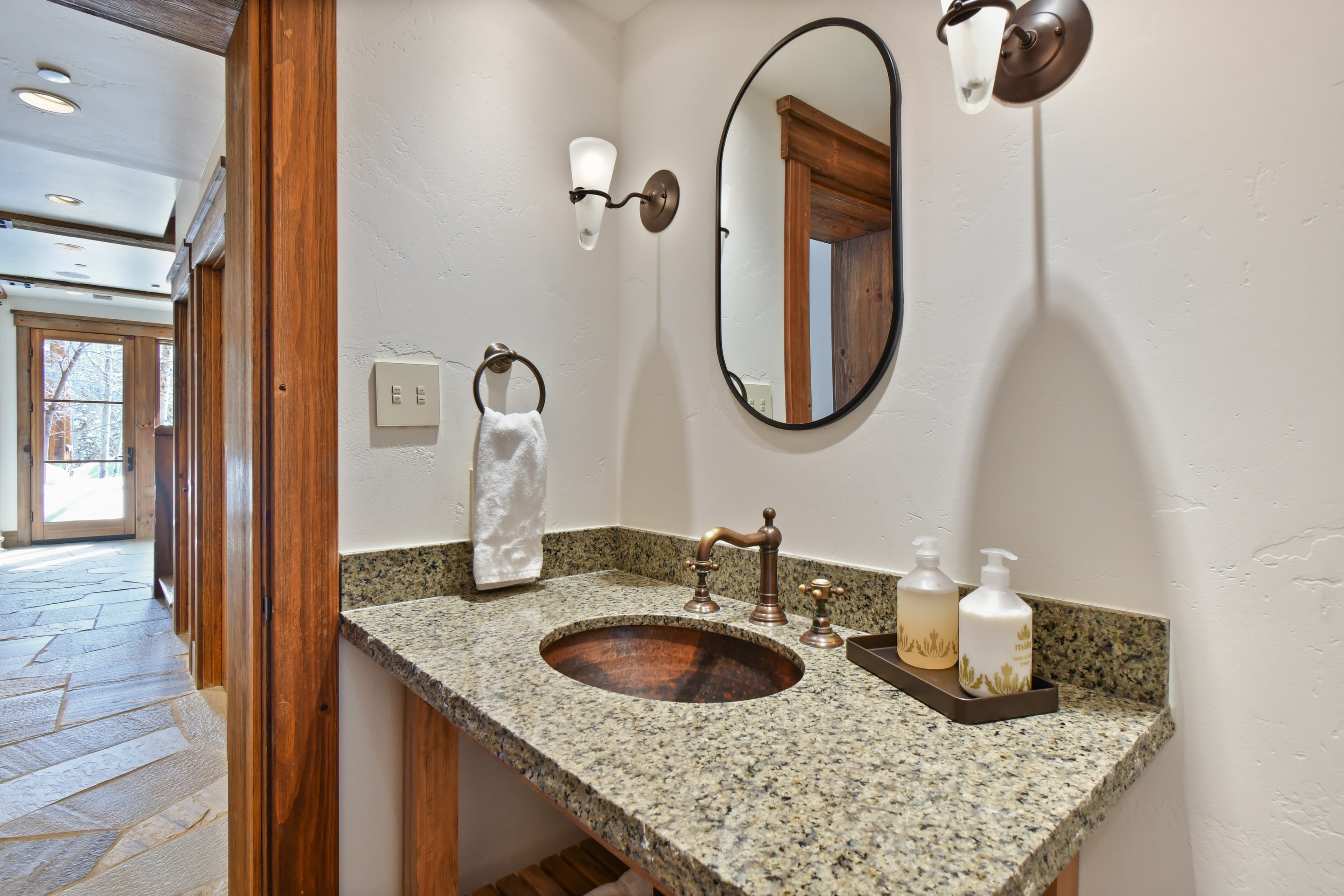 A simple ovular mirror hangs over a small sink.