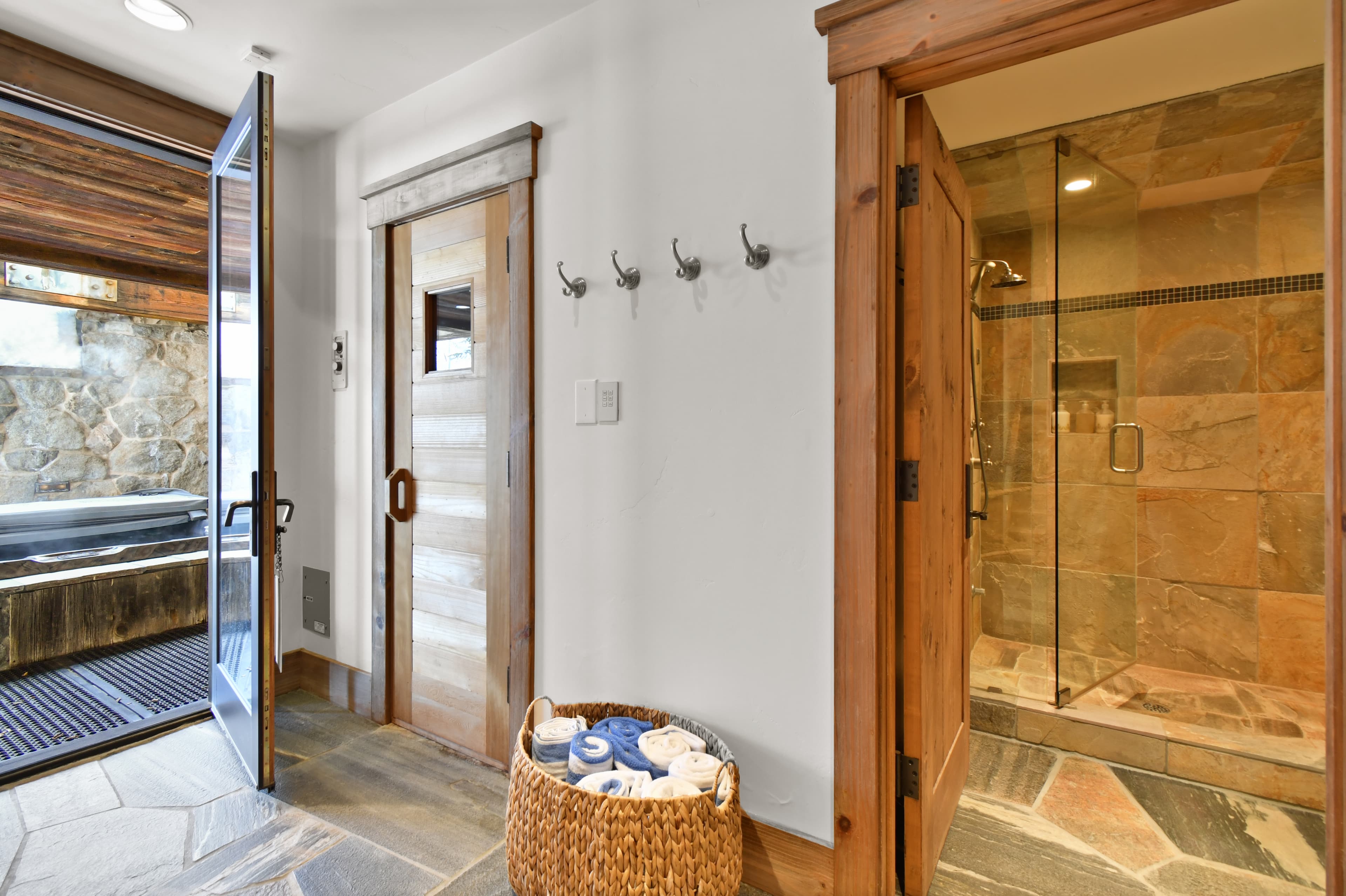 A basket of towels sits next to the doors to the sauna, private bathroom, and private shower.