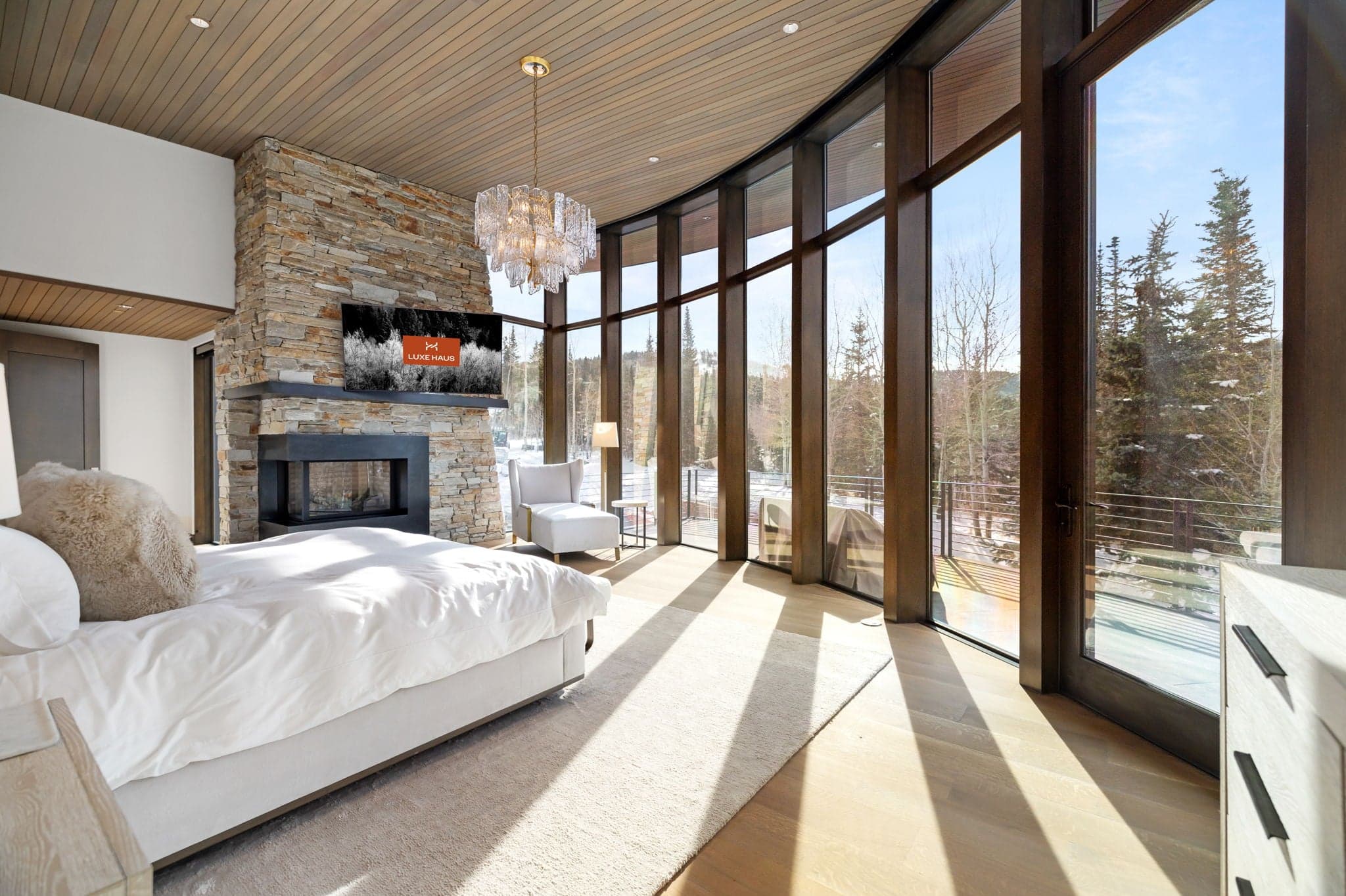 A bedroom with a bed, a fireplace, and a flatscreen tv.
