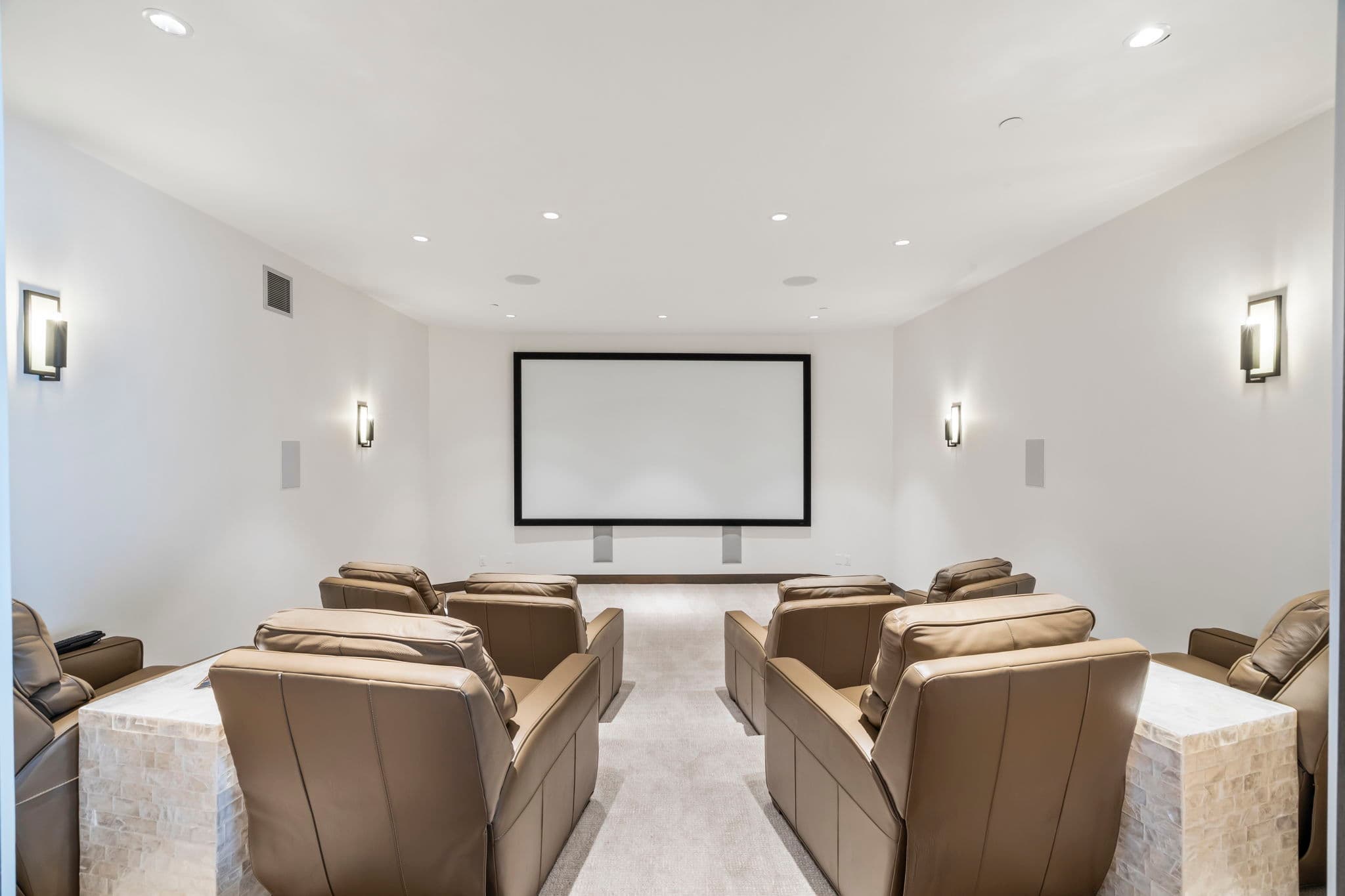 A theater room with a screen and reclining chairs.