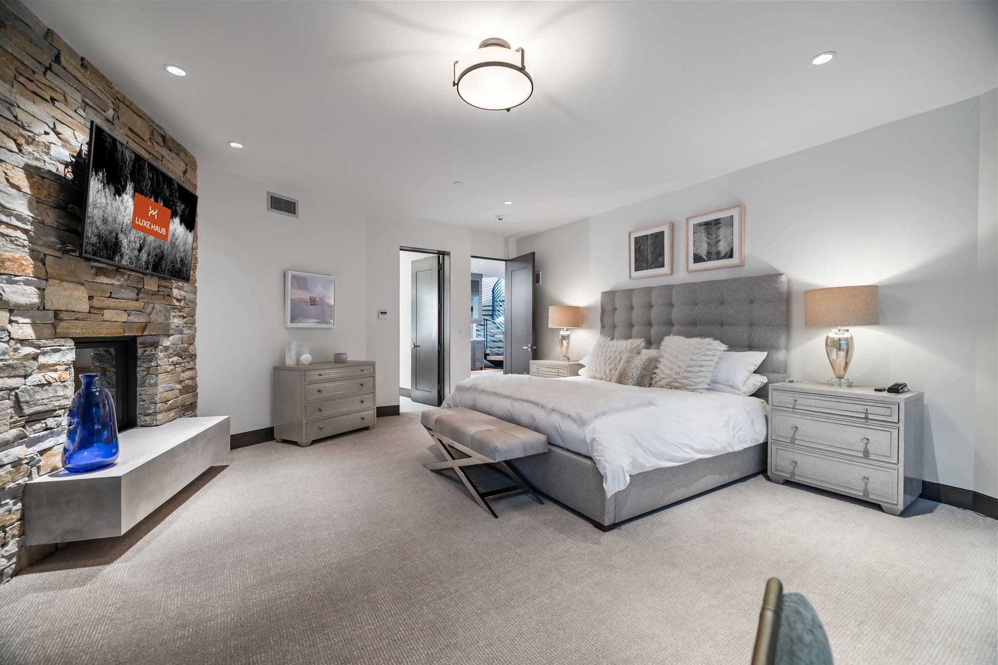 A large bedroom with a bed and a stone fireplace.