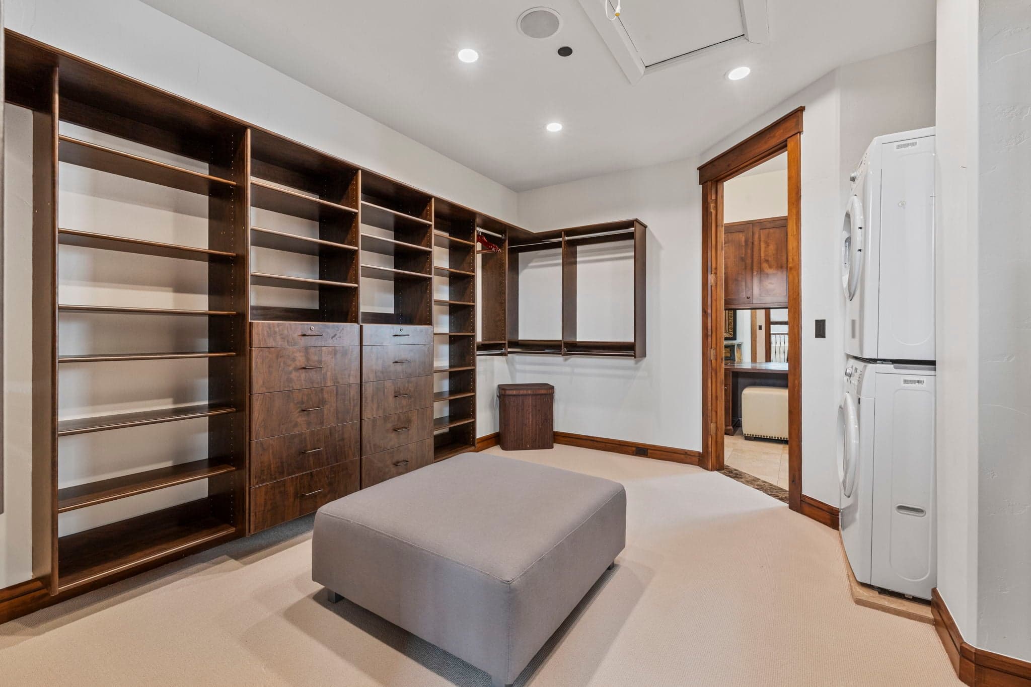 large walk in primary closet with an ottoman in the center